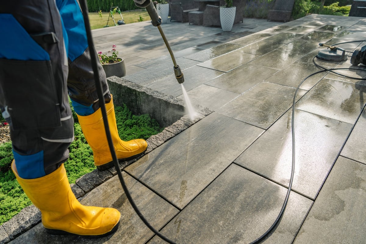 Worker pressure washing a stone patio to restore it to like-new condition